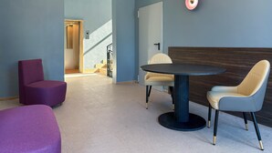 Una habitación moderna con una mesa redonda, dos sillas, un sillón morado y una escalera.
