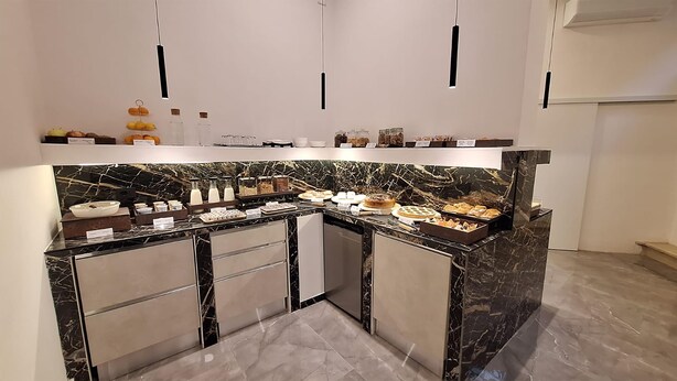 Una cocina moderna con encimeras de mármol, un refrigerador empotrado y diversos alimentos exhibidos en la encimera.