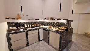 Een moderne keuken met marmeren aanrecht, een inbouwkoelkast en diverse etenswaren op het aanrecht.