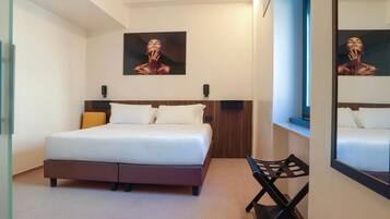 Une chambre à coucher avec un lit, une chaise, un tableau et un miroir.