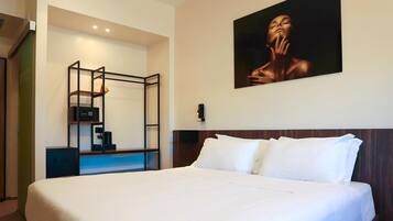 Habitación de hotel con una cama grande, un escritorio con silla, un cuadro en la pared y un armario.