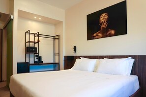 A hotel room with a large bed, a desk with a chair, a painting on the wall, and a wardrobe. - Best Western Hotel Revolution (Rome)