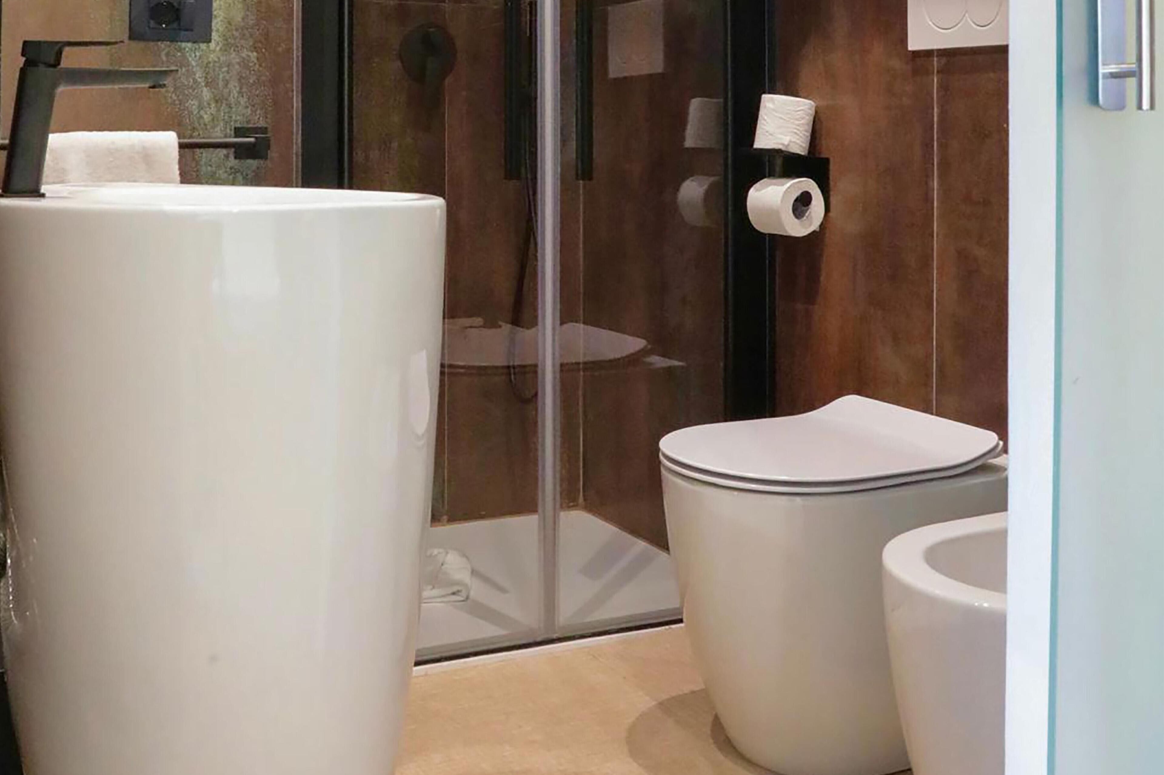 A bathroom with a toilet, a bidet, and a glass shower enclosure.