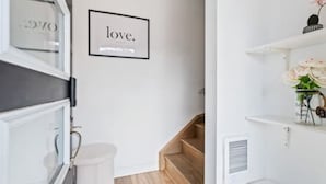 A modern kitchen with white cabinetry, a stainless steel range hood, and a framed sign on the wall that reads "love." - Casa Nova Niagara- New home with a chic and Style (Niagara Falls)