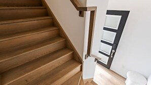 A wooden staircase with a white wall and a door with a black frame. - Casa Nova Niagara- New home with a chic and Style (Niagara Falls)