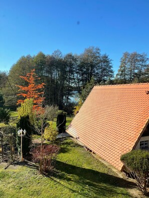 A house with a sloped red-tiled roof, surrounded by a well-maintained garden with various shrubs and a small pond. - Newly built apartment with lake view-Teupitzer Str.9 Tornow (Teupitz)
