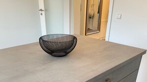 A modern kitchen with a grey countertop, a black woven bowl, and a wooden floor. - Newly built apartment with lake view-Teupitzer Str.9 Tornow (Teupitz)