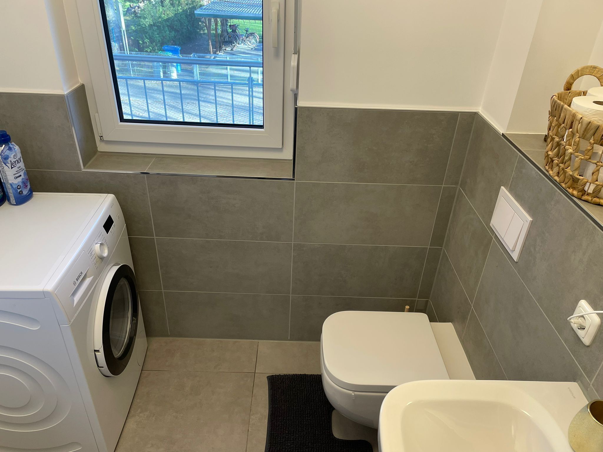 A compact bathroom with a washing machine, a toilet, and a bathtub.