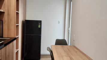 Una cucina compatta con mobili in legno, un frigorifero nero e un'area pranzo con tavolo e due sedie.