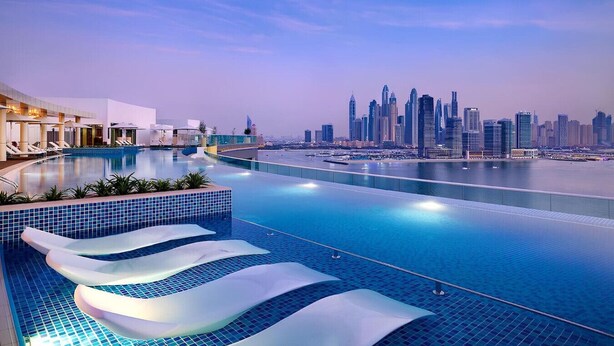 Ein moderner Hotelpool mit Blick auf die Stadt, mit gewölbter Poolkante und Liegestühlen.