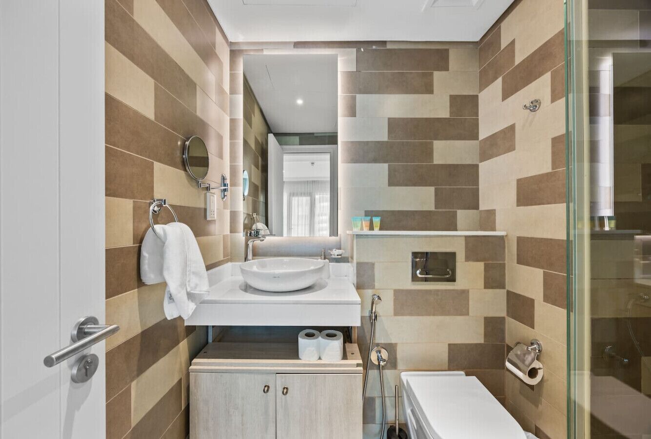 A modern bathroom with a tiled backsplash, a sink, a mirror, and a glass-enclosed shower.