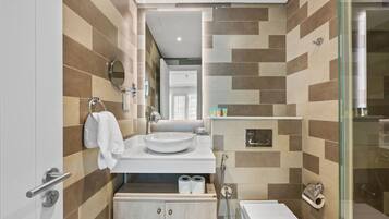 A modern bathroom with a tiled backsplash, a sink, a mirror, and a glass-enclosed shower.