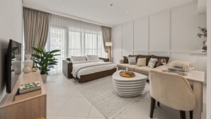 Ein modernes Wohnzimmer mit einer Couch, einem Esstisch, einem Couchtisch und einem Fernseher auf einem Standfuß.