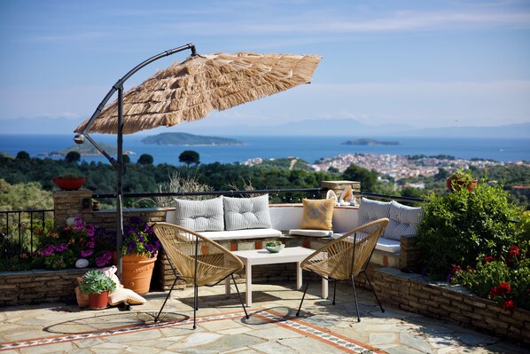 A terrace with a view of the sea, wicker furniture, and potted plants. - Cozy, family-friendly apartment with a view! (Skiathos)