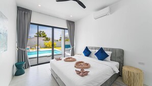 Ein modernes Hotelzimmer mit einem großen Bett, einem Deckenventilator und Blick auf einen Swimmingpool.