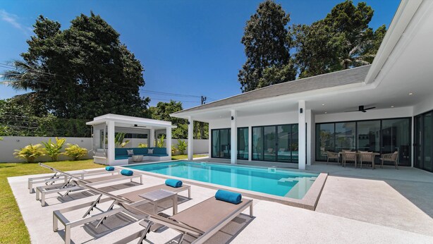 Ein modernes Haus mit Swimmingpool, Sitzgelegenheiten im Freien und einer überdachten Terrasse.