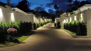 Eine gut beleuchtete, von Bäumen gesäumte Straße, die zu einem Gebäude mit modernem Design führt.
