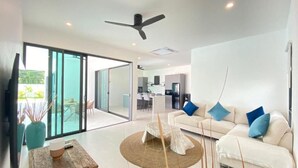 Ein stilvolles Wohnzimmer mit einem weißen Sofa, einem Holztisch und einem großen Fenster.