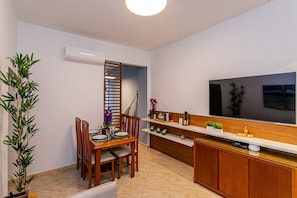 Cozinha moderna com área de jantar, televisão e uma planta.