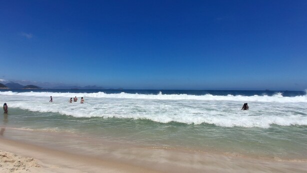 Ein Strand mit Wellen und Menschen im Wasser.