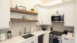 A modern kitchen with white cabinets, a black stove, a microwave, and a dishwasher.