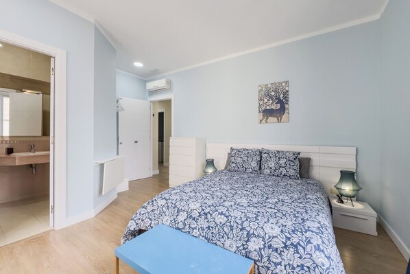 A bedroom with a bed, bedside lamps, a nightstand, a wall-mounted artwork, and a bathroom with a mirror and sink. - STUDIO 4 NEXT TO THE RAMBLAS IN BARCELONA (Barcelona)