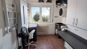 Uma cozinha compacta com micro-ondas embutido, uma pequena janela com vista e piso de madeira.