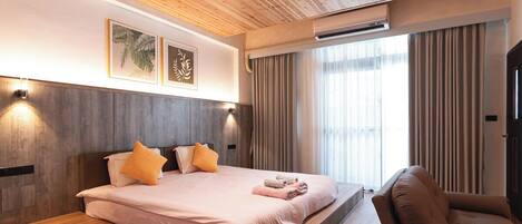 Una habitación de hotel moderna con una cama grande, techo de madera y vistas al exterior.
