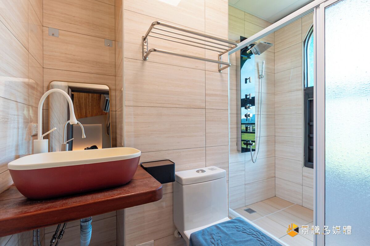 A modern bathroom with a large red sink, a toilet, and a shower area.
