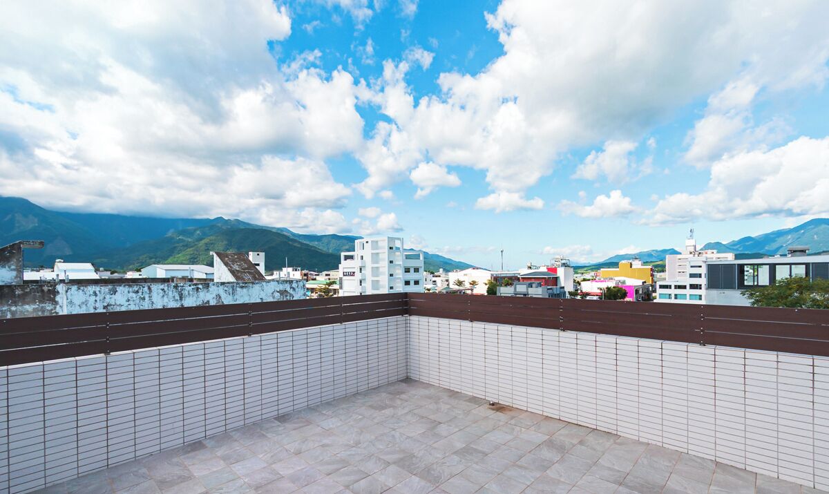 A rooftop terrace with tiled flooring and a view of a cityscape and mountains.