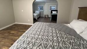 Een slaapkamer met een groot bed, een houten hoofdeinde en een klein raam.