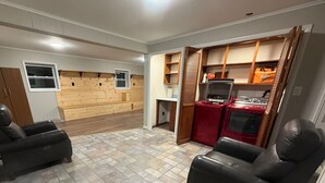 Een wasserette met een houten wand, een wasmachine, een droger en een kleine tafel.