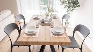 A dining table set with plates, glasses, and cutlery, surrounded by black chairs. - [Leopoldo Cozy Loft] Tram| Air C. | Smart TV (Firenze)
