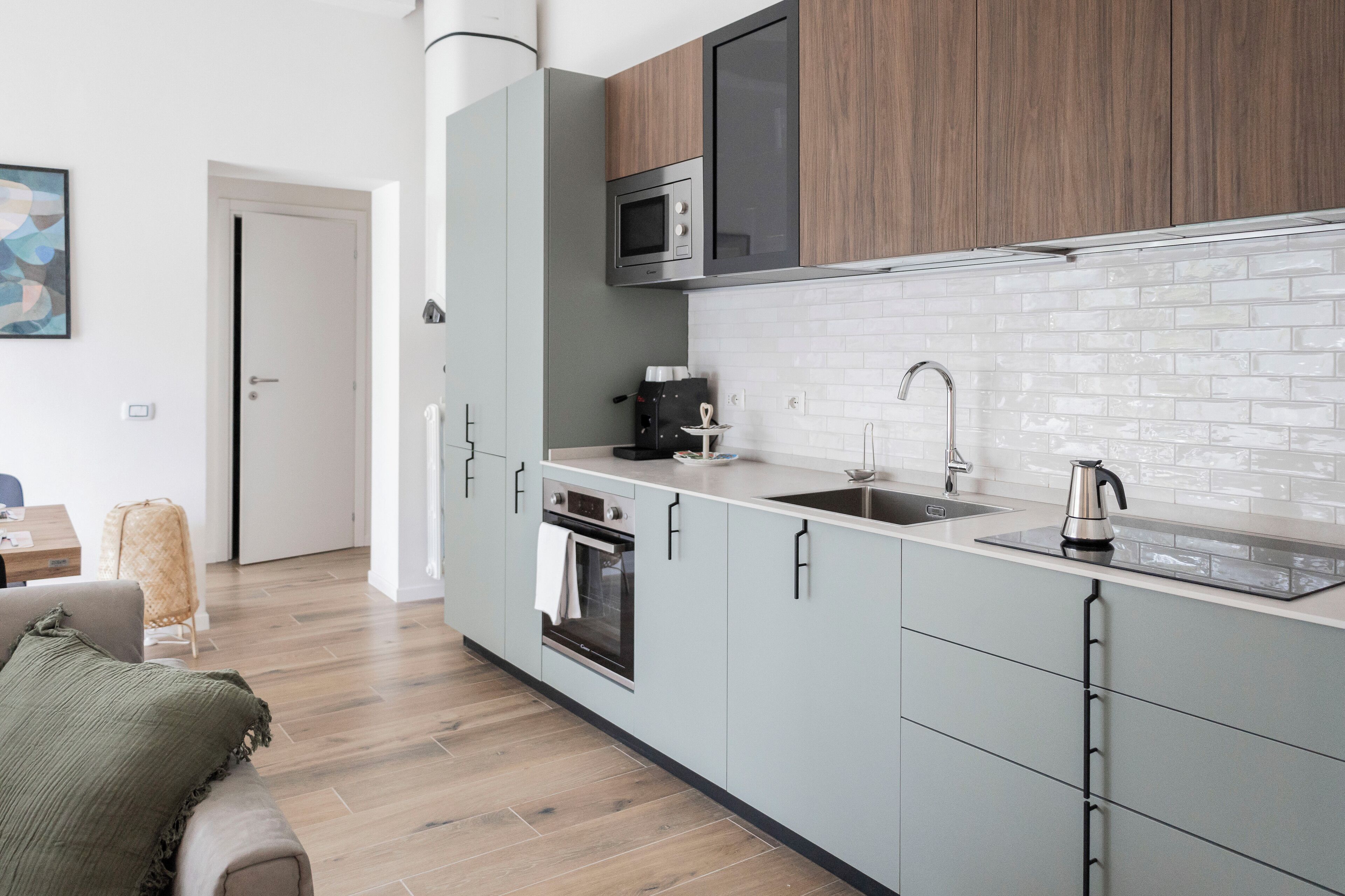 Een moderne keuken met grijze kastjes, een magnetron, een koffiezetapparaat en een spoelbak.