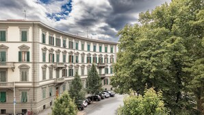 A large, multi-story building with a curved facade, green shutters, and a row of parked cars in front. - [Leopoldo Cozy Loft] Tram| Air C. | Smart TV (Firenze)