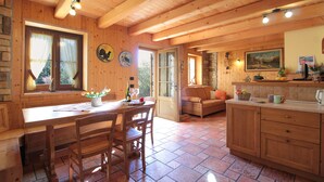 Un interior de madera con una mesa de comedor, sillas, un sofá y una zona de cocina con una encimera y armarios.