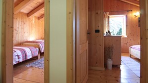 Una cabaña de madera con dos habitaciones, cada una con una cama y una ventana. Hay una puerta que da a un baño.