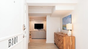 A hallway with a wooden console table, a television, and a painting on the wall. - War College Friendly Downtown Condo (Newport)
