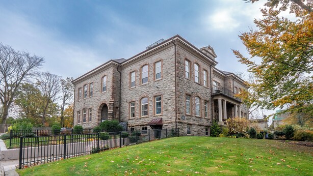A large stone building with a symmetrical facade, multiple windows, and a central entrance with columns. - War College Friendly Downtown Condo (Newport)