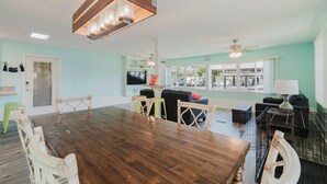 A spacious living area with a wooden dining table, light blue walls, and a large window offering a view of the outside. - Waterfront Escape • Private Dock • Near 3 Sisters Springs (Crystal River)