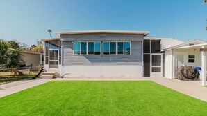 A modern two-story house with a large front lawn and a covered patio area. - Waterfront Escape • Private Dock • Near 3 Sisters Springs (Crystal River)