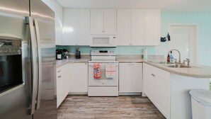 A modern kitchen with white cabinets, stainless steel appliances, and a wooden floor. - Waterfront Escape • Private Dock • Near 3 Sisters Springs (Crystal River)