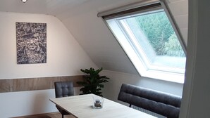 A dining area with a table, chairs, a bench, a potted plant, and a skylight. - Holiday Apartment Ruhrort, 70 sqm with Private Terrace, Garden and Wi-Fi (Brilon)