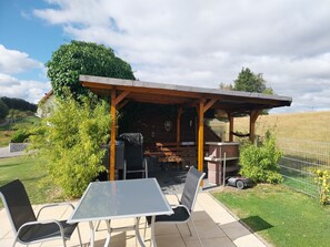 An outdoor patio with a table and chairs, a covered seating area, and a view of the surrounding landscape. - Holiday Apartment 'Ferienwohnung Ruhrort' with Private Terrace, Garden and Wi-Fi (Brilon)
