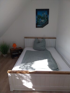 A bedroom with a bed, a nightstand, a lamp, a framed picture on the wall, and a potted plant. - Holiday Apartment Ruhrort, 70 sqm with Private Terrace, Garden and Wi-Fi (Brilon)