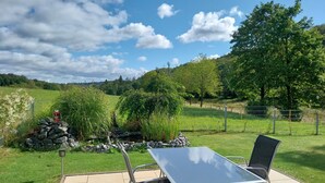 An outdoor patio with a table and chairs, surrounded by a stone wall and greenery. - Holiday Apartment Ruhrort, 70 sqm with Private Terrace, Garden and Wi-Fi (Brilon)