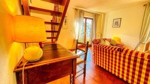 A cozy room with a checkered sofa, a wooden desk with a lamp, a chair, and a staircase. - Appartamento Pietro Micca 60 - Affitti Brevi Italia (Bardonecchia)