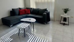 A modern living room with a sectional sofa, a small round table, and a potted plant.