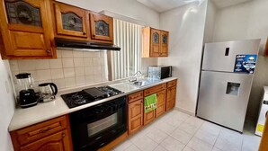 A modern kitchen with wooden cabinets, a stove, a dishwasher, a refrigerator, and a microwave.