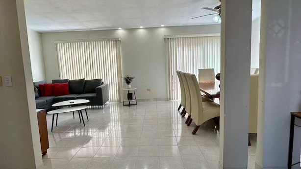 A spacious living area with a sofa, dining table, and chairs.